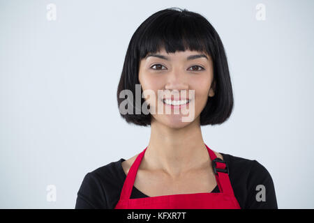 Portrait of smiling waitress standing against white background Stock Photo