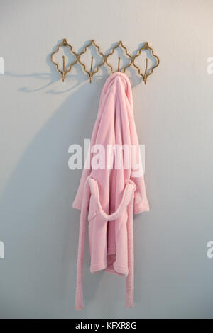 Bathrobe hanging on hook against white wall Stock Photo