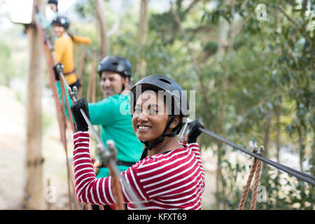 Friends enjoying zip line adventure in park on a sunny day Stock Photo