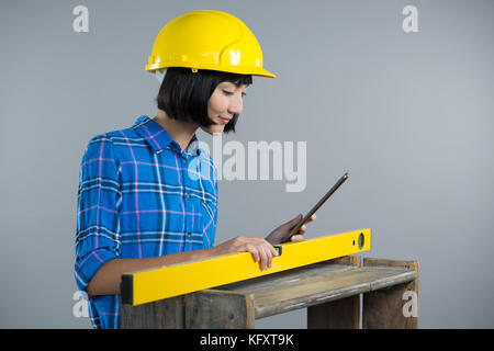 Female architect measuring plywood with engineer scale against grey background Stock Photo