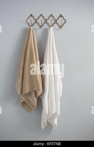 Towels hanging on hook against white wall Stock Photo