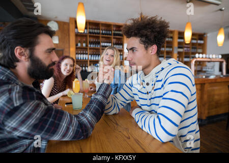 Confident two men arm wrestling in bar Stock Photo
