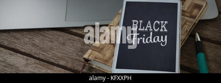 Laptop, mobile phone, dairy and pen on wooden plank against black friday Stock Photo