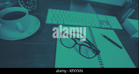 Spiral notepad with black coffee and spectacles on table Stock Photo