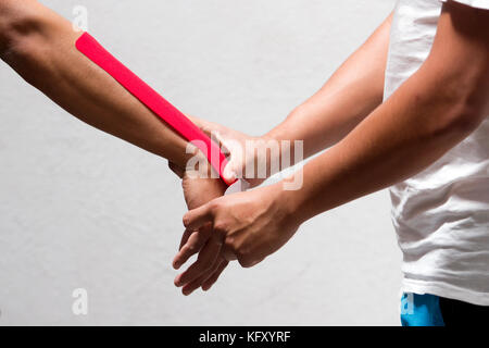 Horizontal photo of a doctor physiotherapist with applying kinesio taping on the arm of a male cyclist Stock Photo