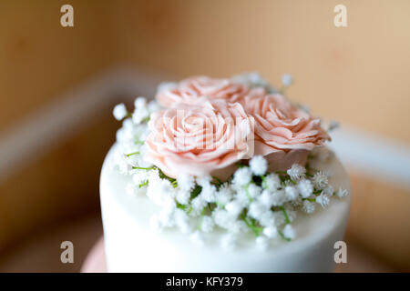 Close up of a pink icing fondant rose petals with babies breath decoration on top of a beautiful wedding cake in the UK Stock Photo