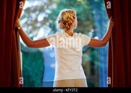 Woman opening curtains Stock Photo