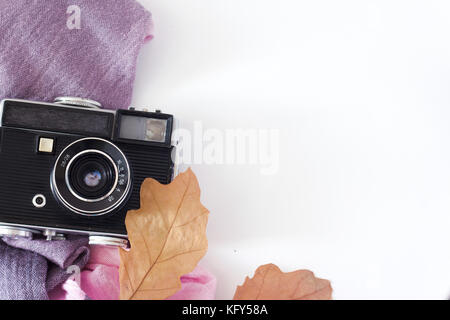 Retro camera and empty old instant paper photo album on wood table with maple leaves in autumn border design - concept of remembrance and nostalgia in