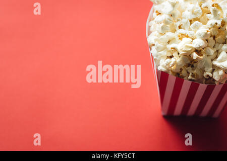 Striped box with popcorn on red background Stock Photo