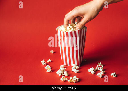 Striped box with popcorn on red background Stock Photo