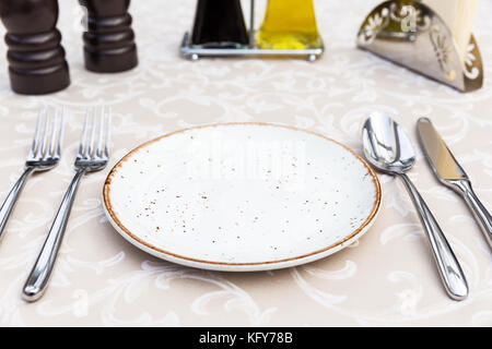 Table setting with plates, knife, fork and spoon, restaurant interior Stock Photo
