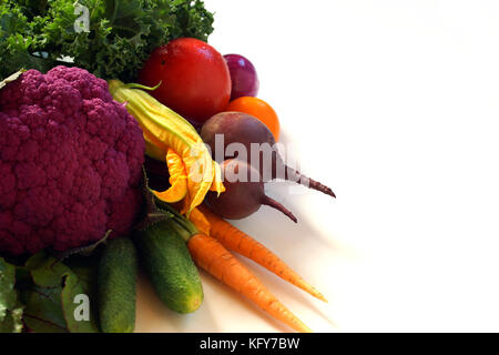 Different vegetables lie on a table: tomatoes, beets, carrots, cucumbers, onions, Purple cauliflower, zucchini flowers, cucumbers end Blue Curled Kale Stock Photo