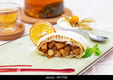 Homemade apple strudel with powdered sugar, vanilla ice cream and mint leaves Stock Photo