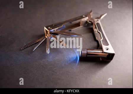 Combined pliers, multifunctional, with flashlight. Against the background of a gray texture. Stock Photo