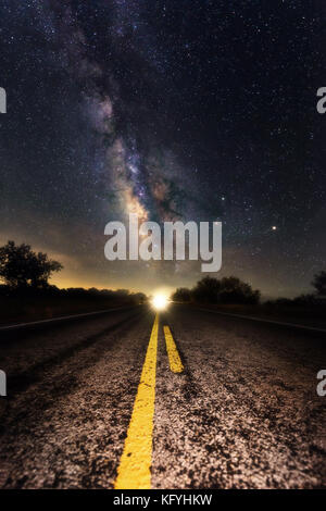 Milky way appear on the middle of the road with double solid yellow line point to the milky way core. Scenic road at night time driving to heaven them Stock Photo