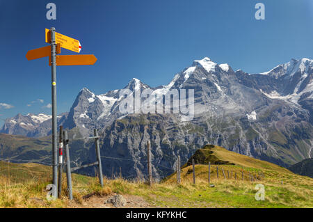 Hiking signpost on Wasenegg ridge on Schilthorn mountain, Eiger, Mönch and Jungfrau in background, Switzerland Stock Photo