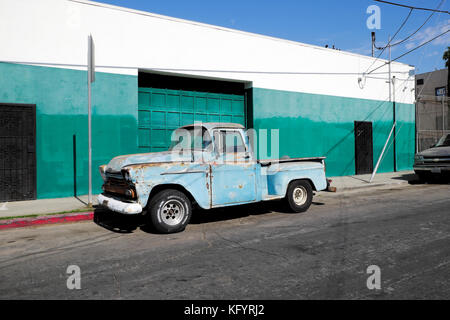 Blue Chevrolet Apache pickup truck parked by a warehouse painted green and white in an Echo Park street in Los Angeles, California USA   KATHY DEWITT Stock Photo