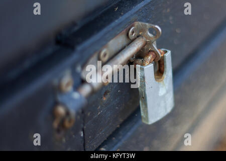 a locked rusty padlock on a sliding bolt latch in the lock position on a timber box Stock Photo