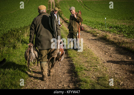 Gentleman carrying shot pheasants on driven shoot day, Hampshire, England.