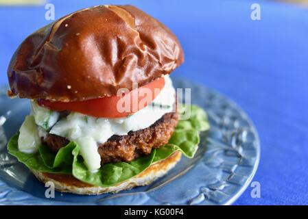 Meatless (meat free) Beyond Burger from Beyond Meat. Vegetarian vegan burger made from peas and other ingredients. Toppings tomato, spinach, cheese. Stock Photo