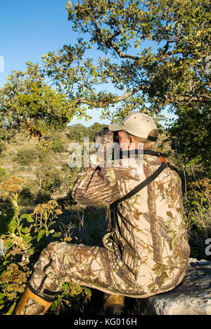 A LONE HUNTER LOOKS FOR WHITETAIL DEER IN THE TEXAS HILL COUNTRY Stock Photo