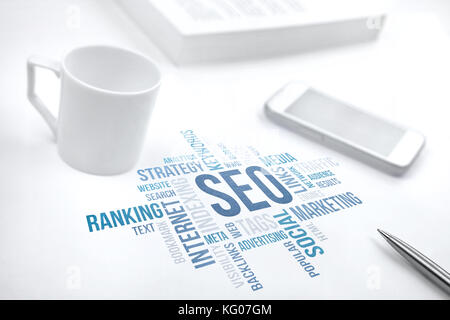 Seo, search engine optimization, business concept word cloud. Print document, smartphone, book, pen and coffee cup. Blue toned. Stock Photo