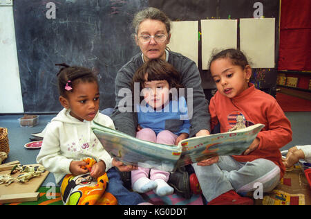 Teacher reading to a group of children at a nursery school Stock Photo