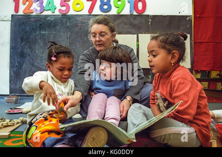 Teacher reading to a group of children at a nursery school Stock Photo