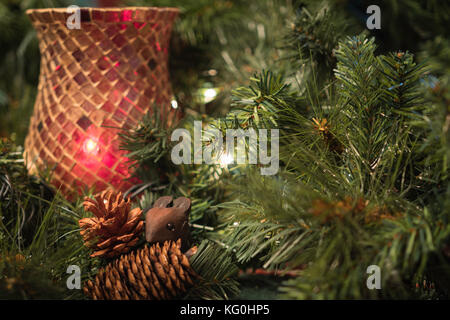 Christmas display with brass candlesticks, greenery, pine cones, and a red  ball ornament Stock Photo - Alamy