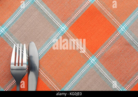 Fork and table knife lying on chequered tablecloth Stock Photo