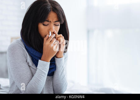 Sad woman using nasal drops at home Stock Photo