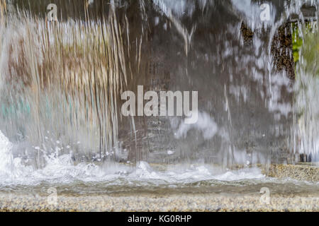 waterspout fountain detail including a water surface with small waves, water drops and splashes in stony ambiance Stock Photo