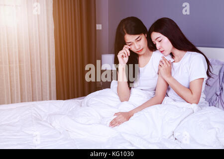woman having problem and woman cheers her up on bed in the bedroom Stock Photo