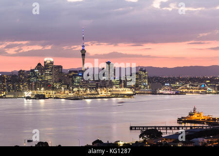 Sunset over Auckland central business district skyline and the harbor taken from the Davenport hill viewpoint in New Zealand largest city. Stock Photo