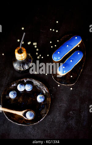Blue eclairs and candy in blue colors. On a dark background. Pastry arts Stock Photo