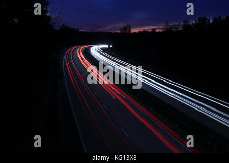 Car light trails at night on motorway in sunset Stock Photo