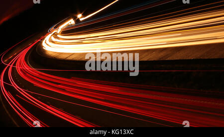 Car light trails at night on motorway in sunset Stock Photo