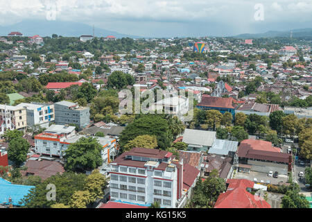 High view over buildings and rooftops of Manado City, North Sulawesi, Indonesia, with Mount Klabat looming in the distance. Stock Photo