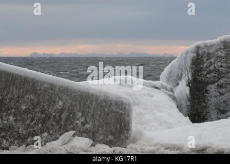 Stones by the coast is covered with ice after a storm in Vestfjorden, Norway Stock Photo