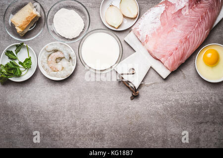 Fish patties cooking ingredients: raw fish fillets, egg,flour, soaked bread, shrimps, seasoning on concrete background, top view, border Stock Photo