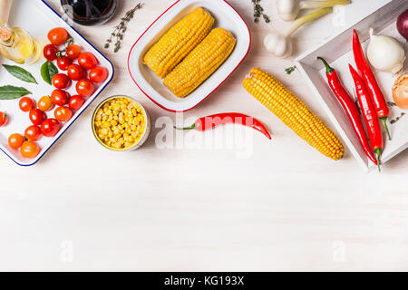 Cooking preparation with ear of corn, canned and cooked corn and ingredients for vegetarian dish on  white wooden kitchen table background, top view,  Stock Photo