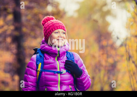 Hiking woman with backpack looking at inspirational autumn golden trees and woods. Fitness travel and healthy lifestyle outdoors in fall season nature Stock Photo