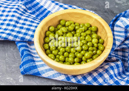 Canned peas in a wooden plate on a gray concrete background Stock Photo