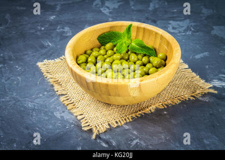 Canned peas in a wooden plate on a gray concrete background Stock Photo