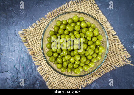 Canned peas in a wooden plate on a gray concrete background Stock Photo