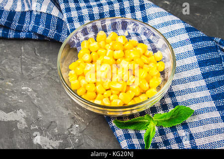 Canned corn in a glass plate on a gray concrete background Stock Photo