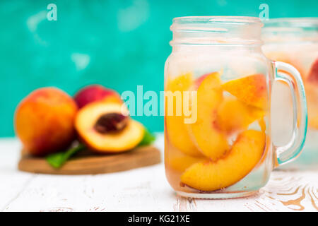 Homemade iced lemonade with ripe peaches. Fresh peach ice tea in a mason jar. Stock Photo