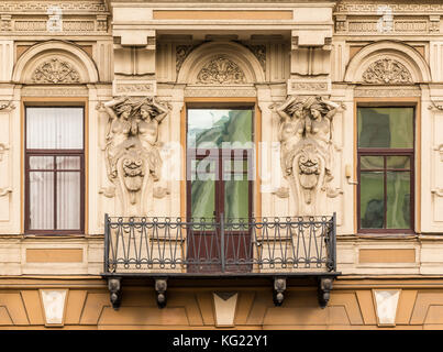 Three windows in a row, balcony and sculptures on facade of urban office building front view, St. Petersburg, Russia