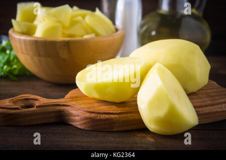 Raw peeled and sliced potatoes on an old weathered wooden table Stock Photo