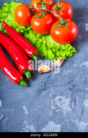 Red chili peppers, tomatoes, Sadat and garlic on a gray marble background Stock Photo